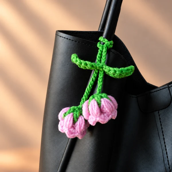 Pink lily of the valley crochet charm on a black bag